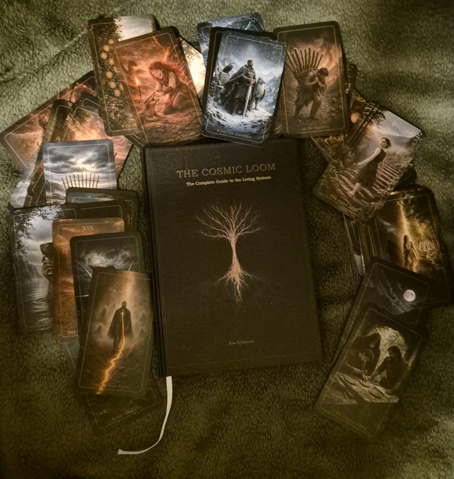 Fotografi av The Cosmic Loom-guideboken omgiven av tarotkort